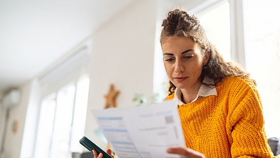 female orange sweater woman reading a document on paper